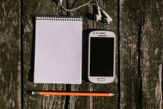 white smartphone with earbuds and notepad