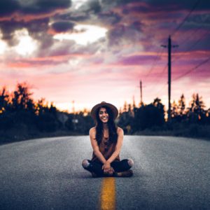 warren-wong-275574-girl-sitting-in-the-middle-of-distant-paved-road-unsplash image