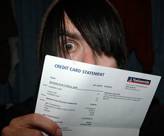 man peeking over the top of a credit card statement